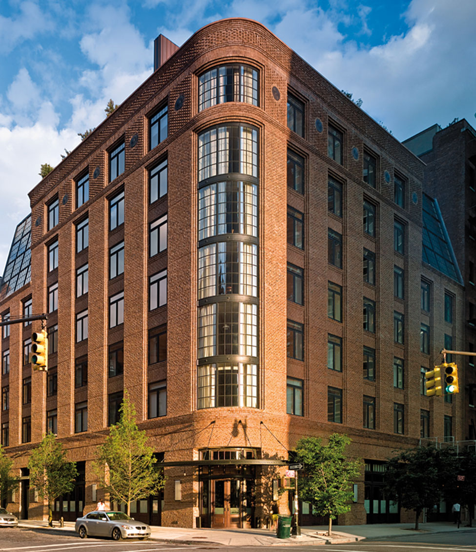 A multi-story brick building with a rounded corner and a street level view.