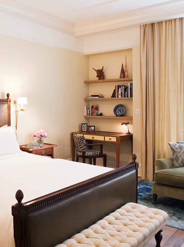 A wide view of a hotel room with a large bed, a desk area with a chair, and a comfortable reading nook.