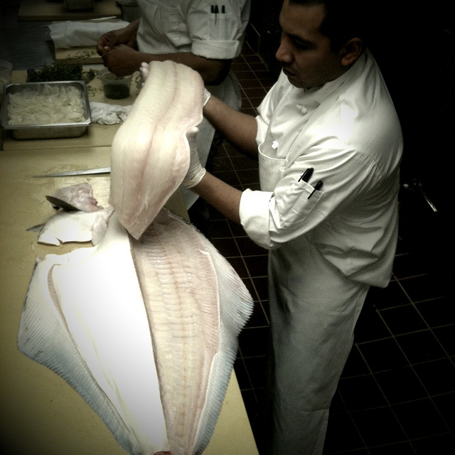 Chef breaking down fish in the kitchen at Locanda Verde