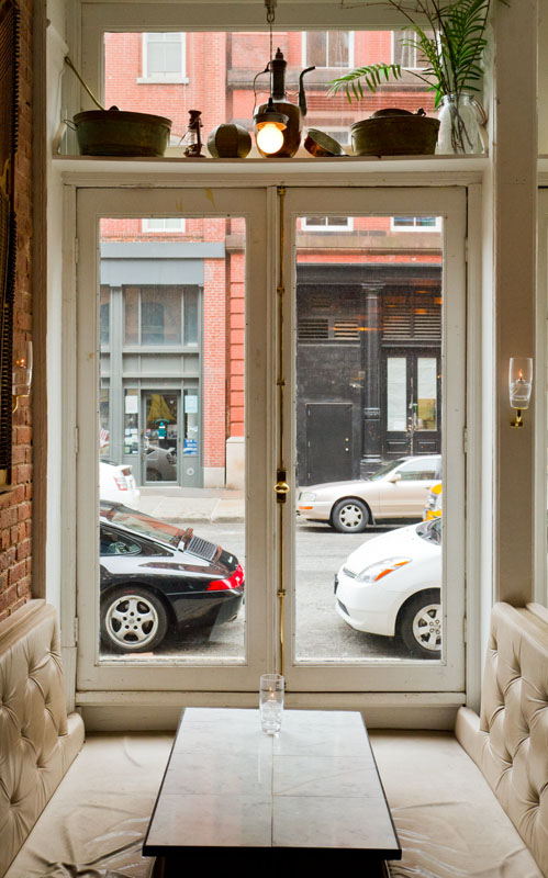 A naturally lit seating area with large windows looking out at the street at Weather Up Cocktail Bar