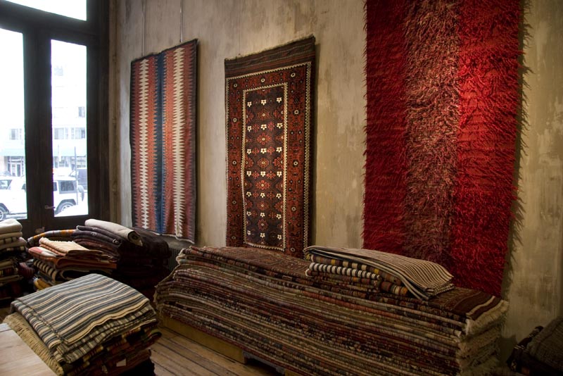 Three mostly red rugs hanging on the wall inside Double Knot