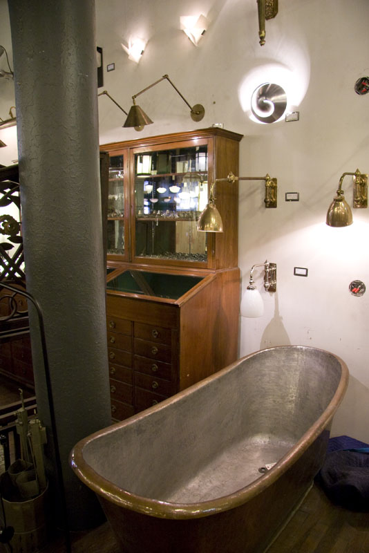 An early metal bathtub and other lighting on display inside Urban Archaeology Antiques and Vintage
