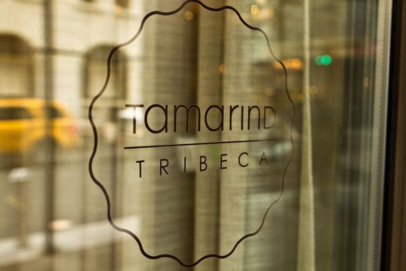 Tamarind Tribeca logo applied to a window with a reflection of street traffic