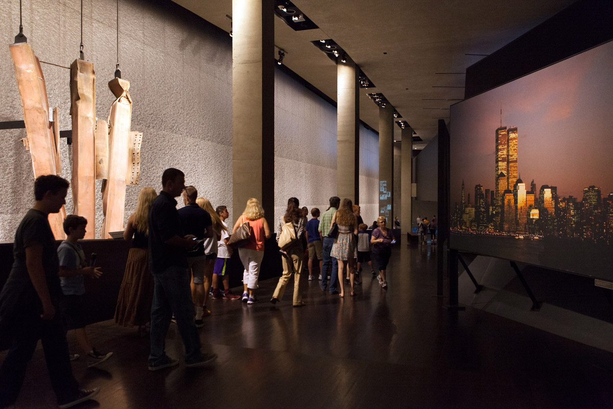 A large group walks through the museum while looking at a original skyline of NYC
