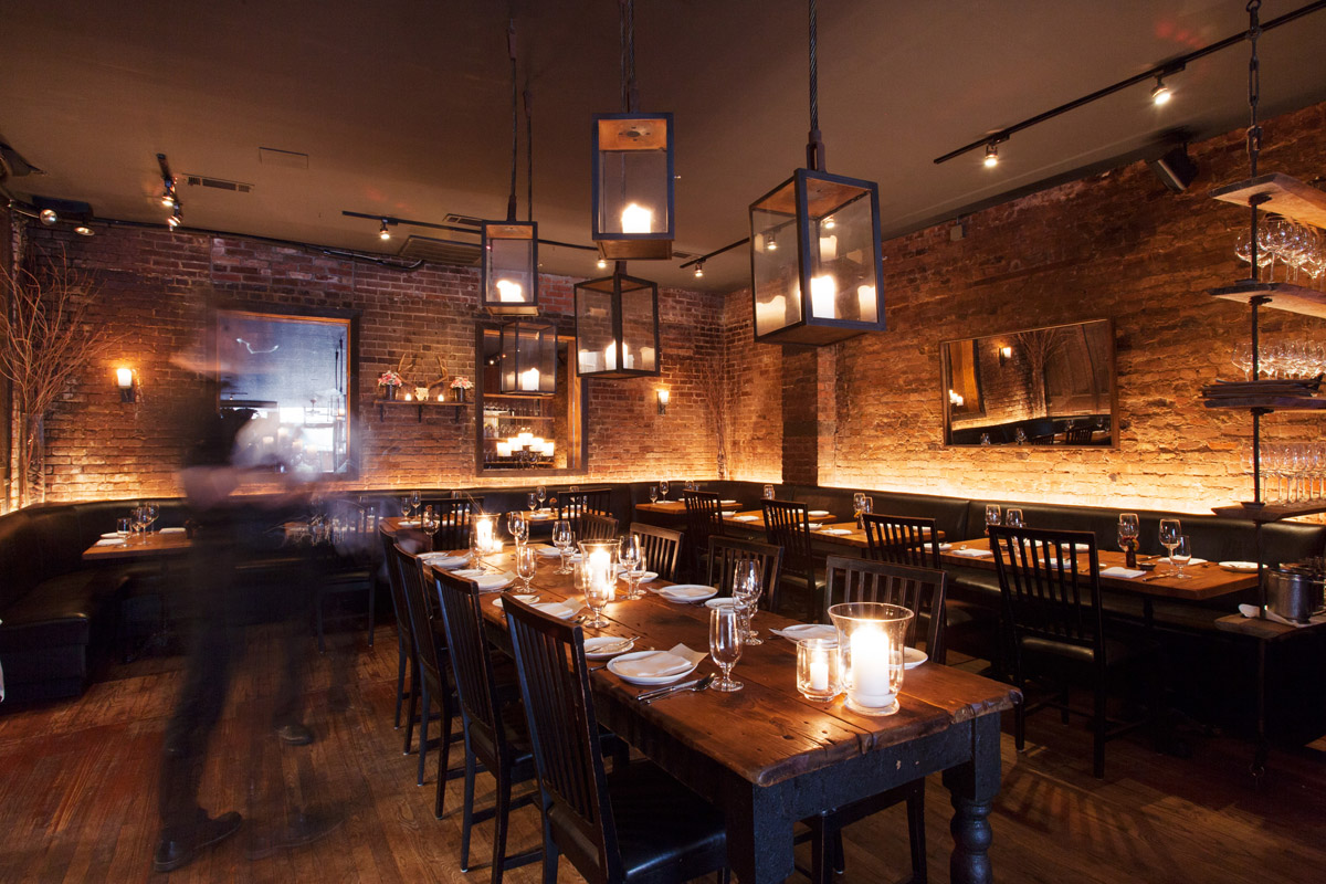 A view of the dining room with a member of the staff moving quickly through the room at Marc Forgione
