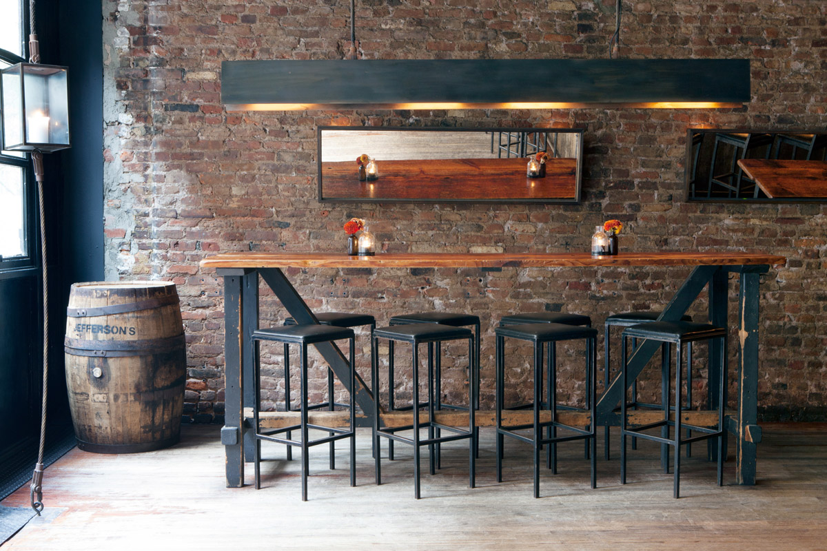 Brick walls and industrial style hi-top table with stools at Marc Forgione