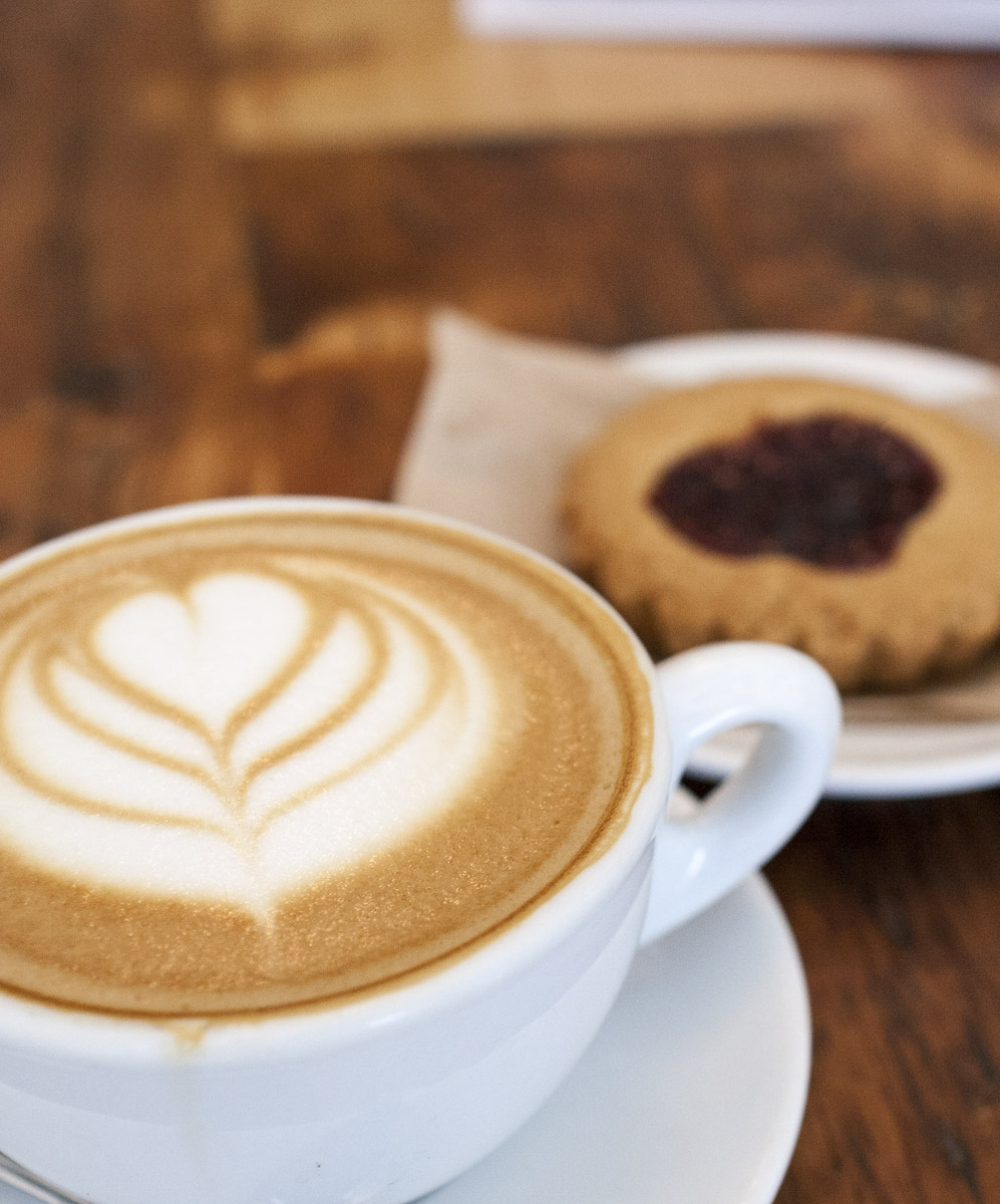 A large cup of latte and pastry on a table inside the cafe