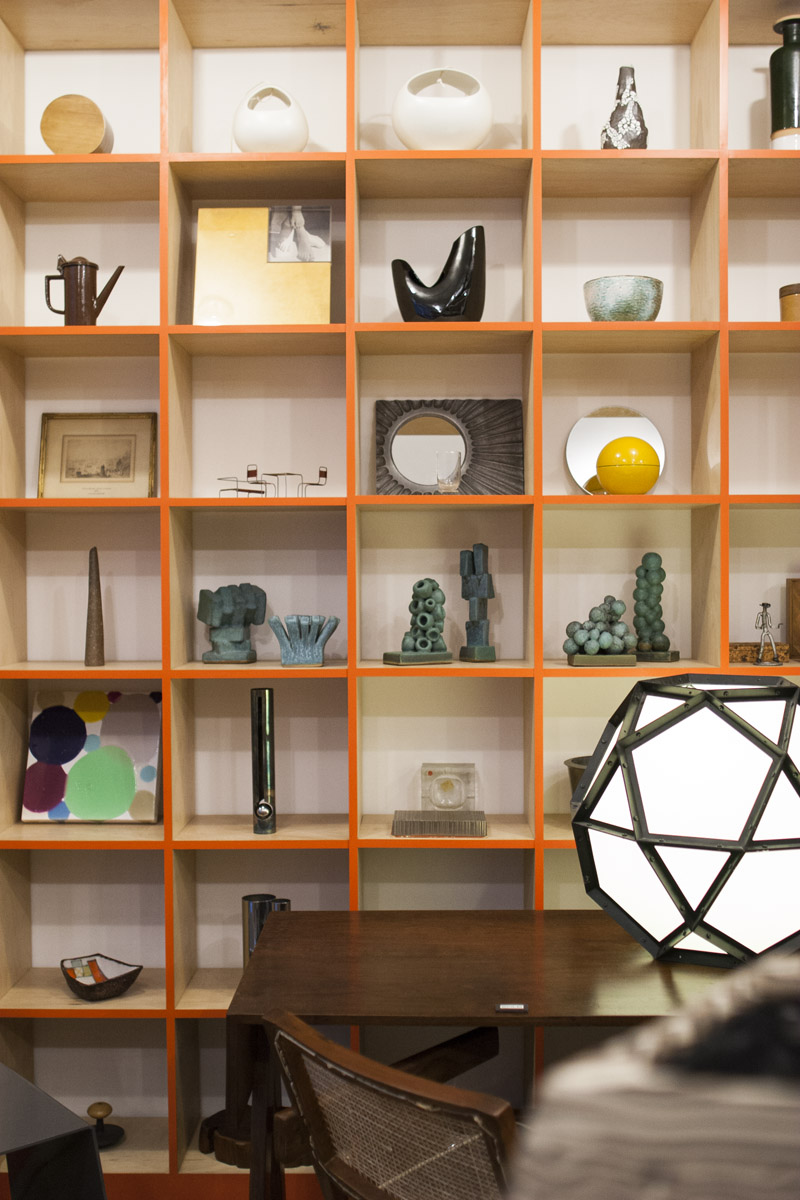 Wall bookshelf display of various design objects inside the gallery