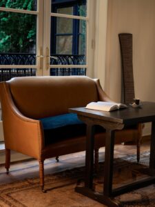 Superior King Room Brown Coach with a blue cushion in front of the balcony doors