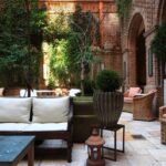 The courtyard at the Greenwich Hotel sofa and chair seating against a green and brick backdrop