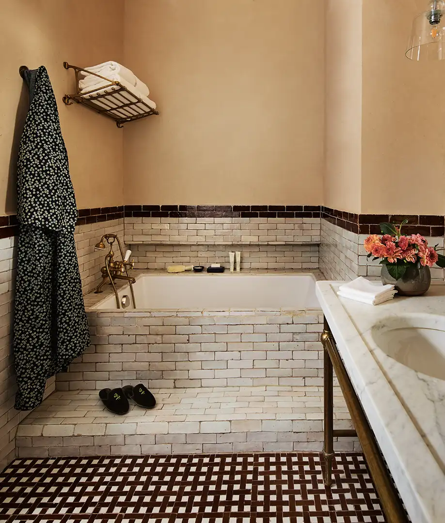 View of the marble vanity and soaking tub with towel rack and robe hanging on the wall
