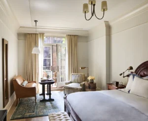 Full view of the deluxe king room with balcony doors and seating area in the background and bed in the foreground.