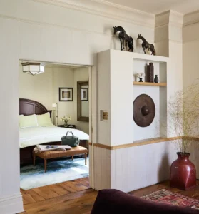 Looking from the living room through the door to catch a glance of the bed inside the bedroom.