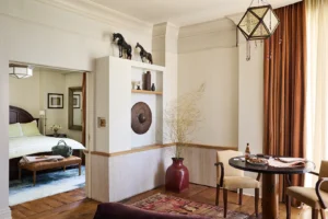 Looking from the living room through the door to catch a glance of the bed inside the bedroom.