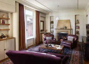 Corner suite living room sofa and leather arm chairs with large window and fireplace in the background