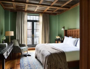 The guest bedroom with wood framed ceiling, green walls and balcony doors