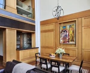 The living room table and kitchen area with custom wood finishes on the wall