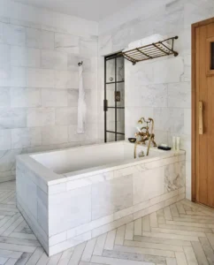 A view of the soaking tub in the middle of the bathroom wall. The walk-in shower door is on the left and the sauna door is on the right