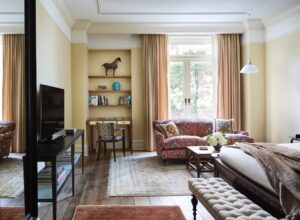 Wide view of a Superior King room. Pictured is the bed, tv, seating area in front of tall glass balcony doors.