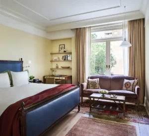 The superior king bed in the foreground. A desk and shelves next to a settee in front of balcony doors in the background