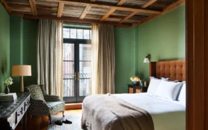 The guest bedroom with wood framed ceiling, green walls and balcony doors