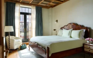 The primary bed room with white walls, king bed, arm chair and bright balcony doors