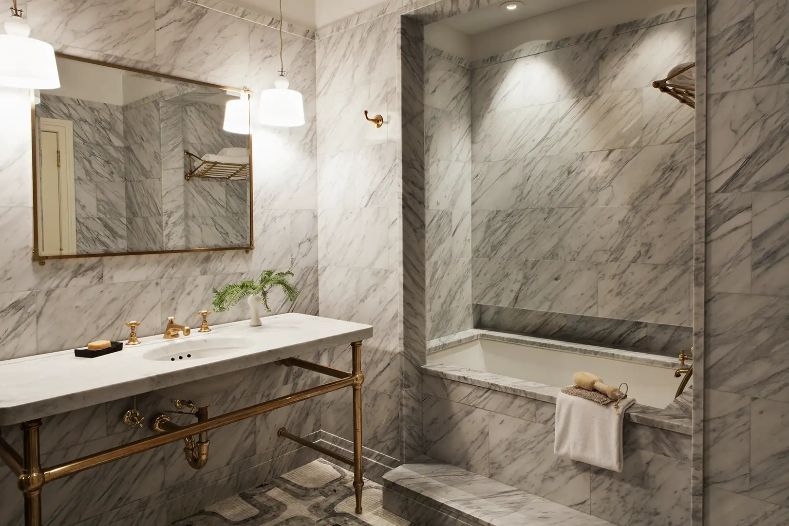 A marble bathroom with alcove soaking tub, vanity and mirror above the vanity