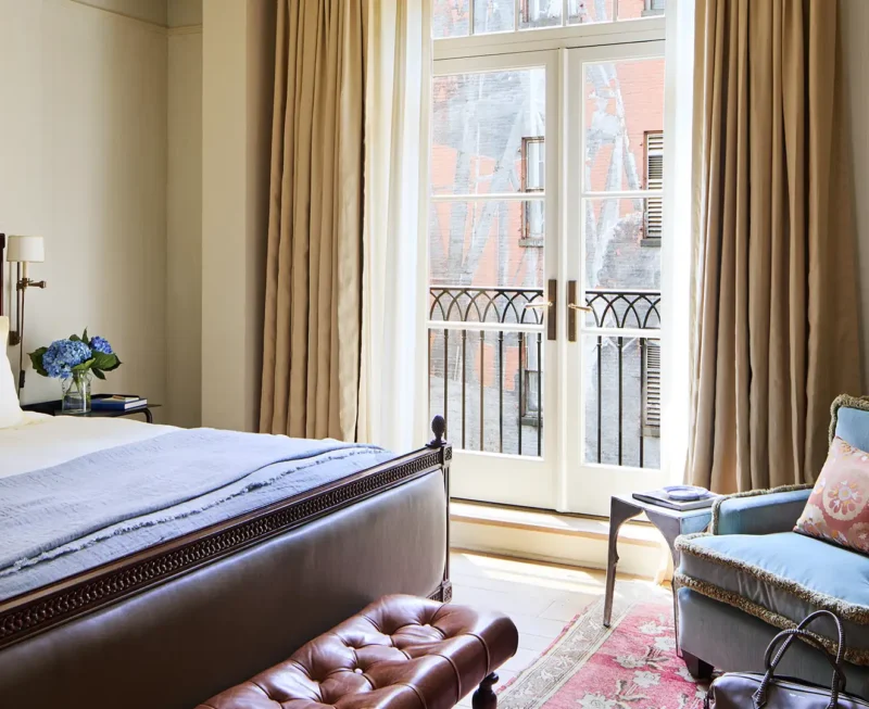 Looking at the balcony doors over the bed with an armchair in the right corner.