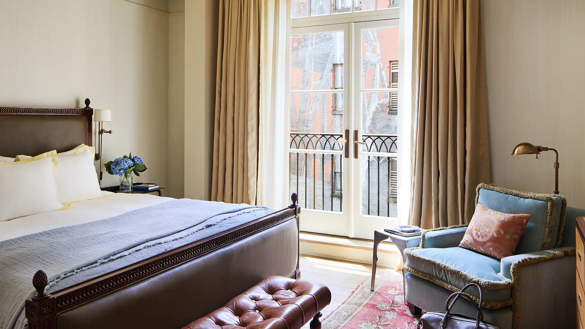Looking at the balcony doors over the bed with an armchair in the right corner.
