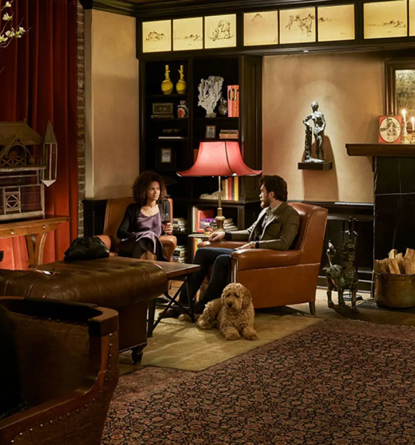 A couple sitting next to the Drawing Room fire place while they dog lays next to them on the floor.