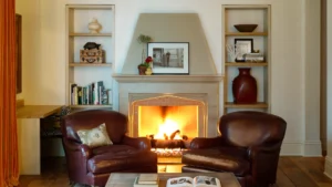 Fireplace Corner Suite looking straight on at the fireplace with active fire. Chairs and Bookshelves with decorations framing the fireplace.