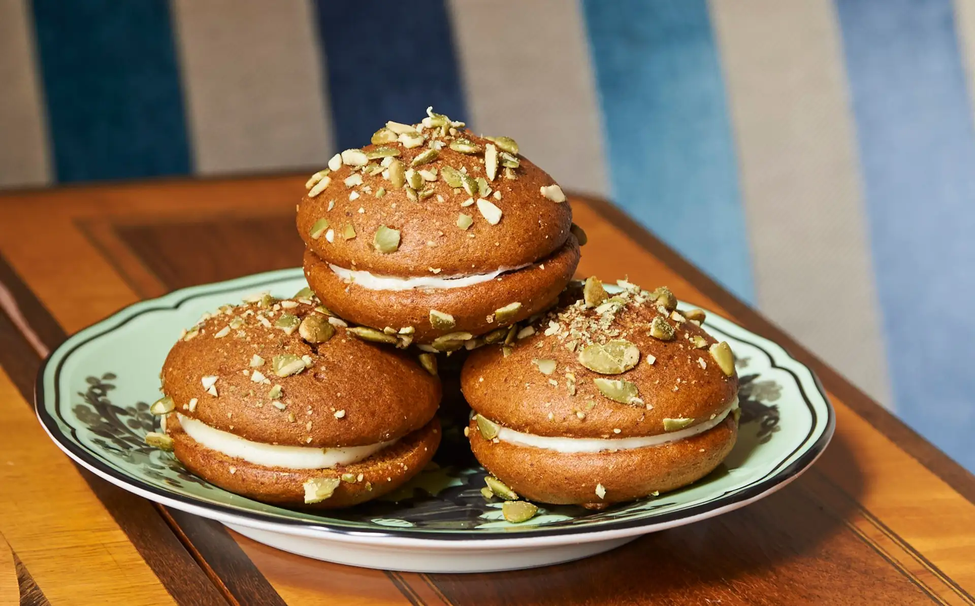 Whoopie pies on a wood table with a striped chair in the background