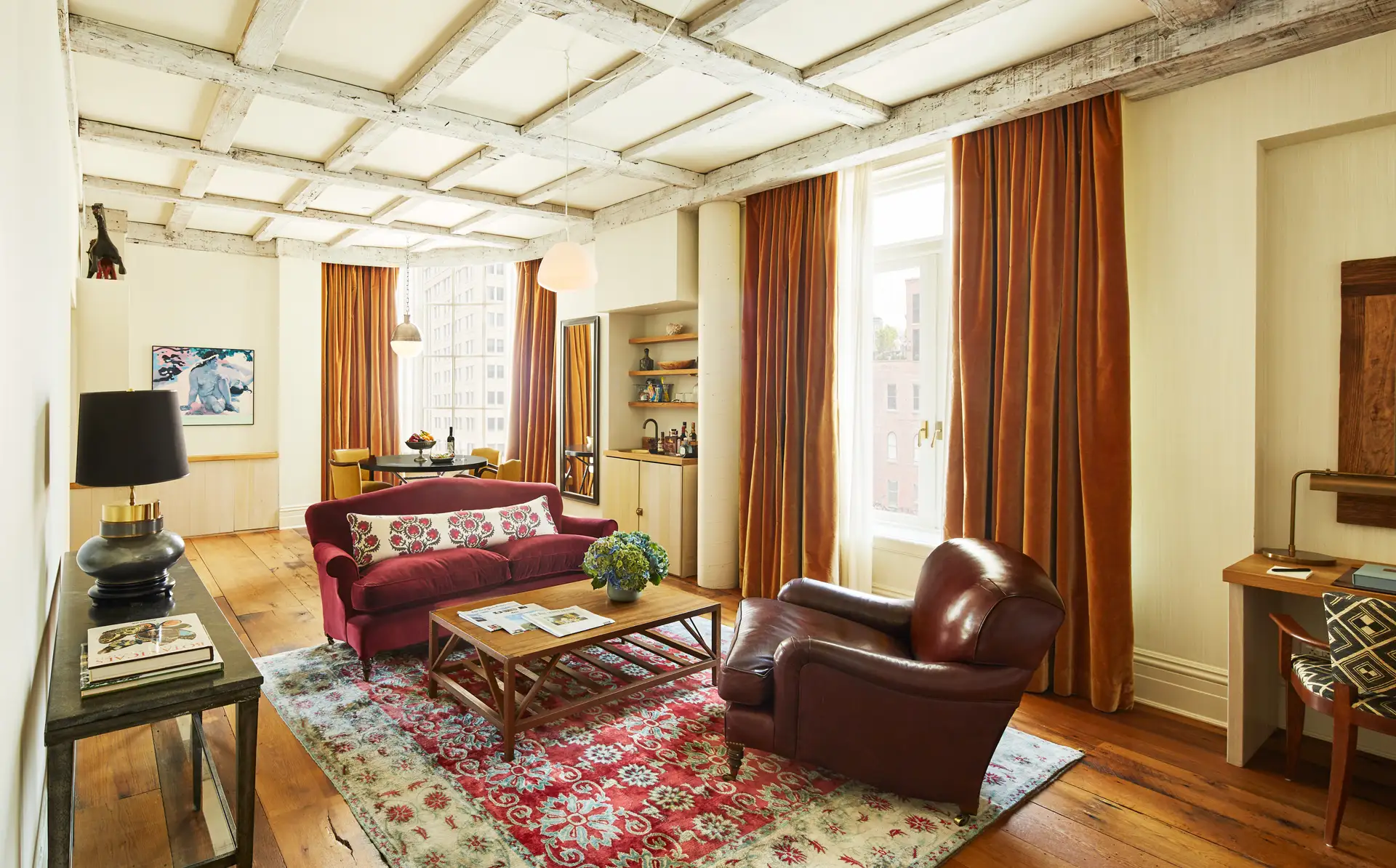 A wide angle view showing the sitting area, bar, desk, and dining table and chairs in the background.