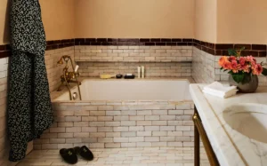 Superior King room with Soaking tub surrounding by brown and white tile. Greenwich slippers next to the tub with a robe and marble vanity.