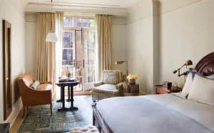 Full view of the deluxe king room with balcony doors and seating area in the background and bed in the foreground.