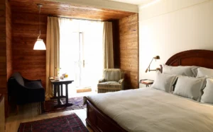 Deluxe king bed room showing part of the bed in the foreground and the wood paneling ceiling and walls in the seating area.
