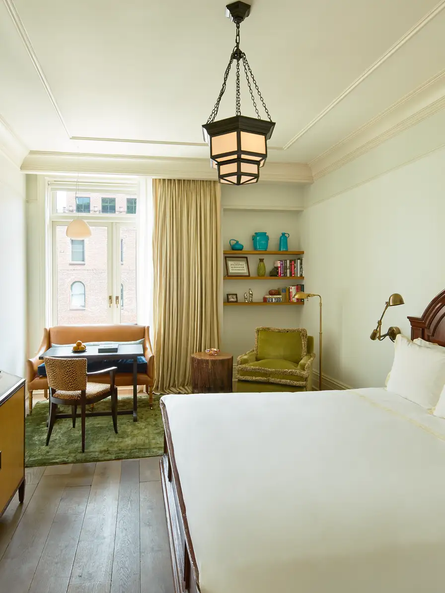 Looking over the king bed at the sitting area against the exterior wall with a large window flooding the room with natural light.