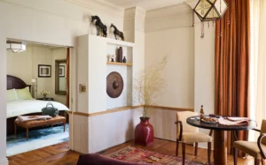 Looking from the living room through the door to catch a glance of the bed inside the bedroom.