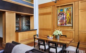 The living room table and kitchen area with custom wood finishes on the wall