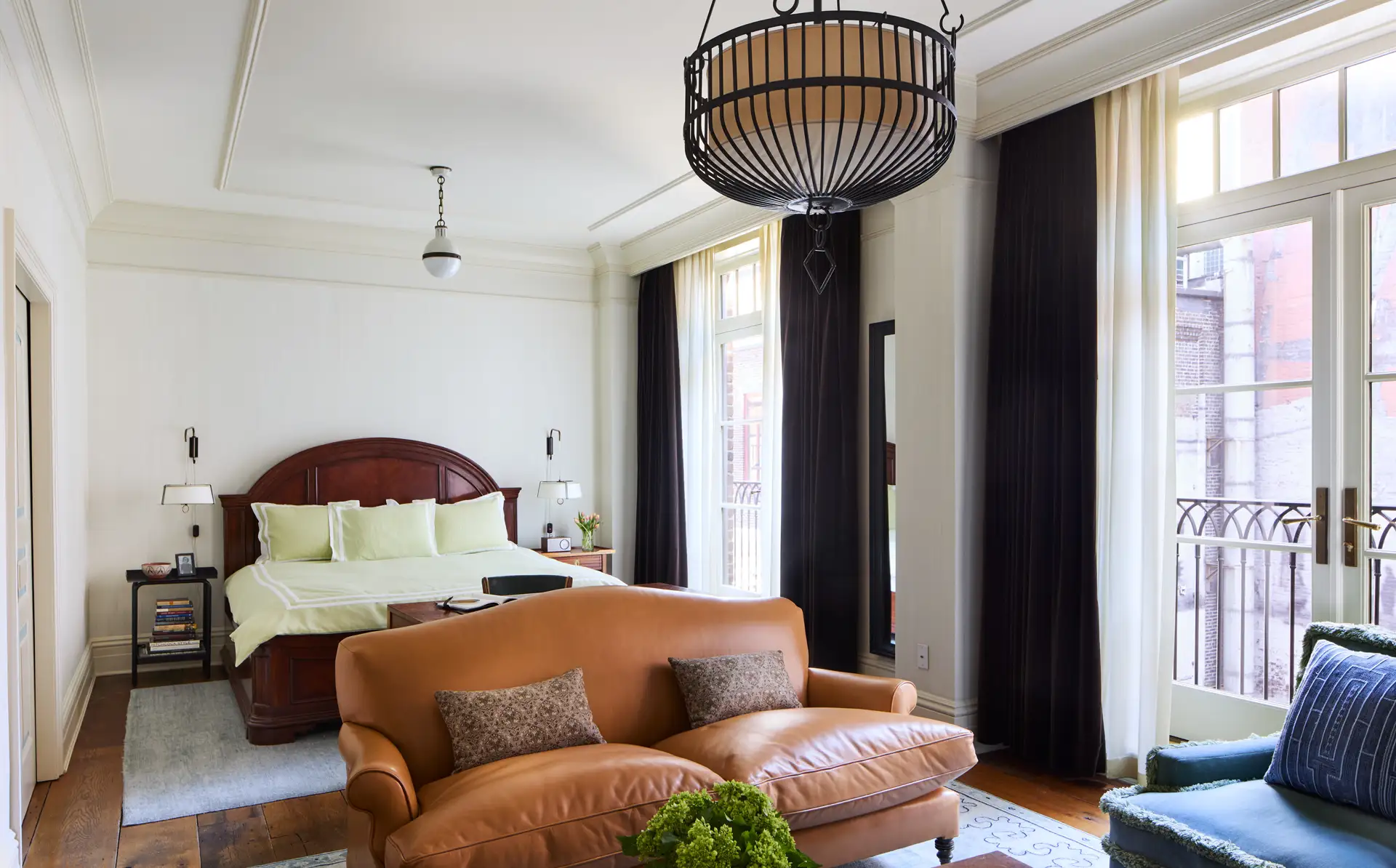 View of the Studio Suite. Looking at from the seating area, over the leather sofa and the king bed in the background. Large windows line the right wall.