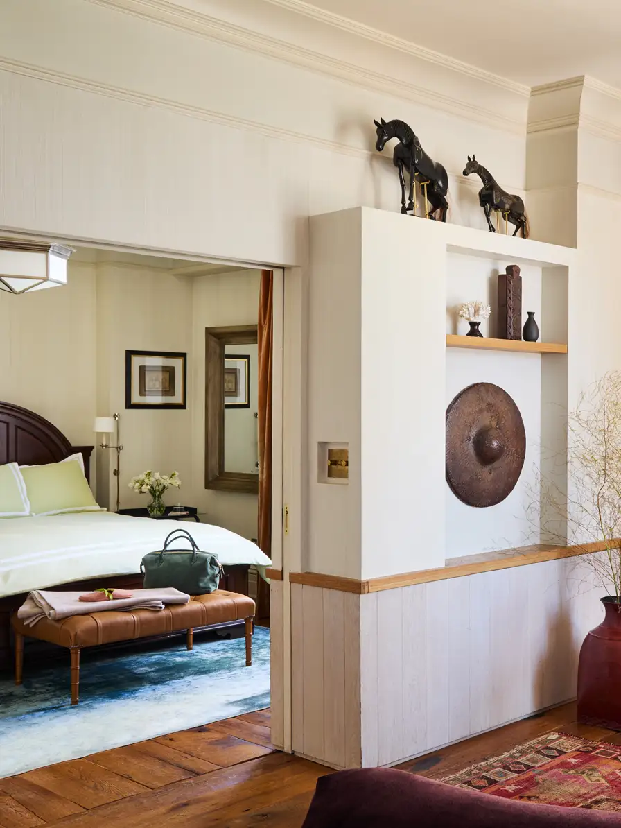 Looking from the living room through the door to catch a glance of the bed inside the bedroom.