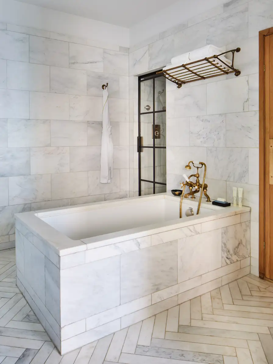 A view of the soaking tub in the middle of the bathroom wall. The walk-in shower door is on the left and the sauna door is on the right