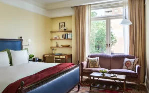 The superior king bed in the foreground. A desk and shelves next to a settee in front of balcony doors in the background