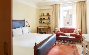 Superior King Room with Soaking Tub Bedroom with sliding privacy door, bed, white dresser, natural light form large window and desk/coffee station.