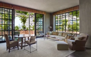 A photo of the naturally lit tribeca penthouse drawing room/seating area with table and chairs, glass doors that open to the balcony and a comfy sofa and chair