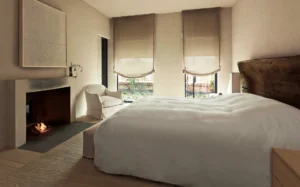 The master bedroom with large fireplace and shades drawn halfway