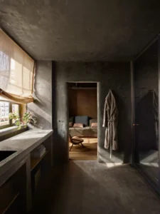 The master bathroom with concrete tones and a robe hanging on the wall next to the open door