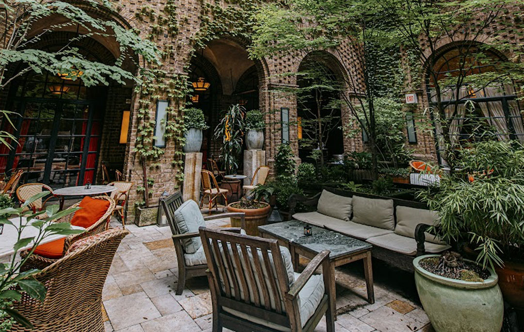 In the secluded Greenwich Hotel courtyard looking through seating at the brick archways