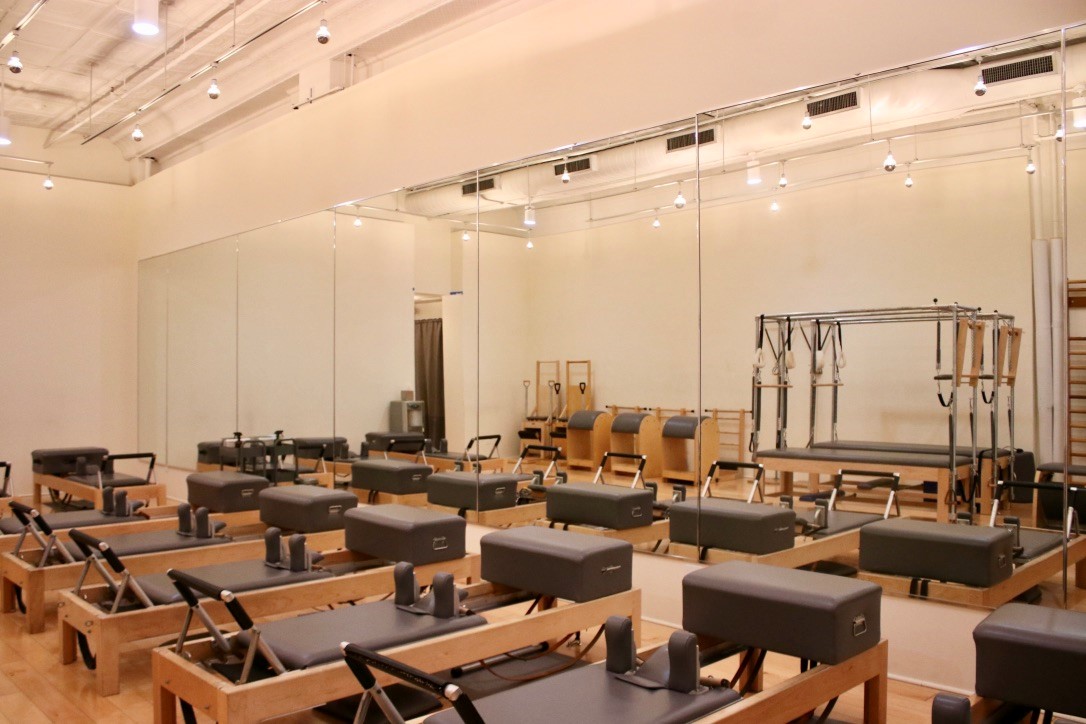 Angle of pilates equipment showing the studio wall of mirrors