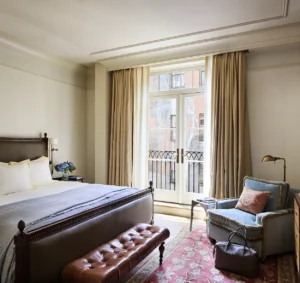 superior king bed and armchair. a mural on the wall outside the balcony doors is visible.